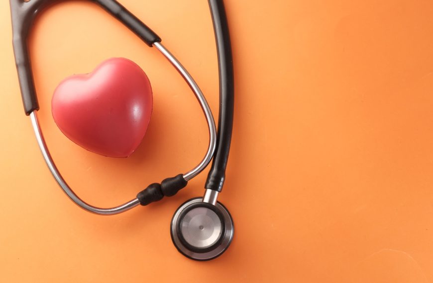 Estetoscopio y corazón rojo sobre fondo naranja, representando la importancia del diagnóstico genético preimplantacional en la reproducción asistida.