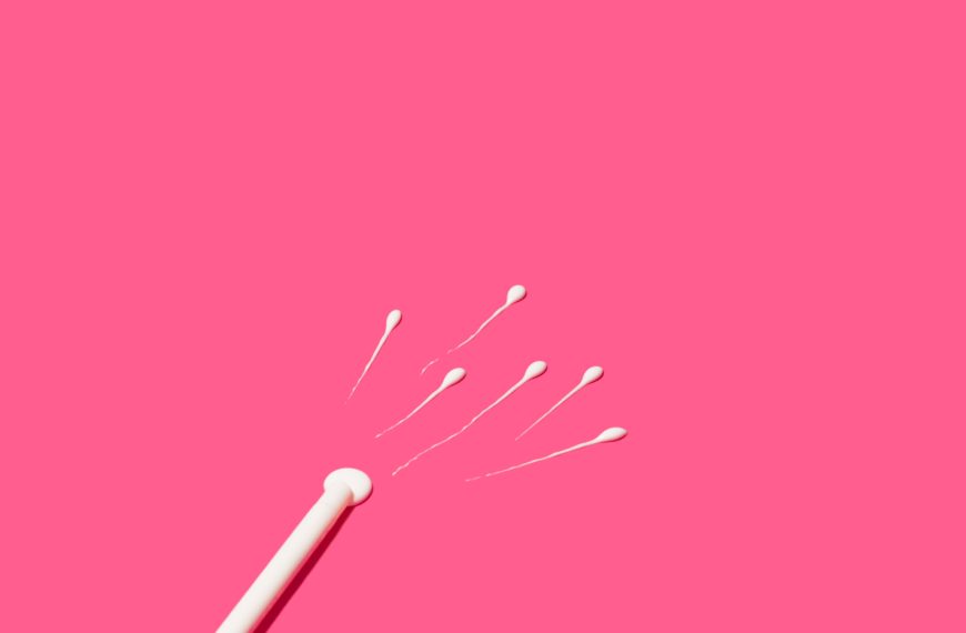 Hisopos de algodón blancos dispersos sobre un fondo rosa liso.